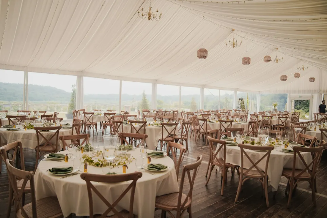 Sample photo: reception tent set with round tables, white linens and cross-back chairs